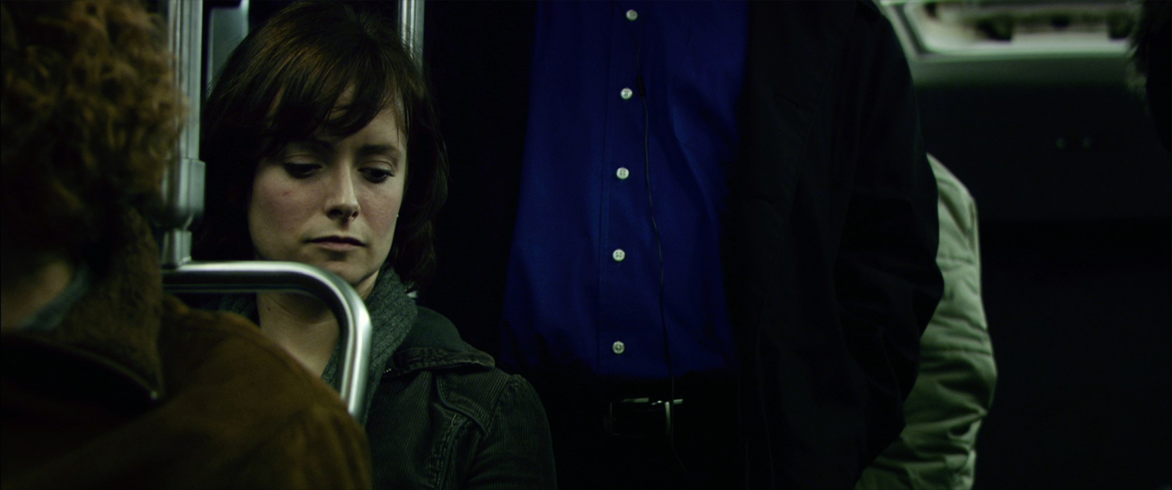 Retina – April Watson on a crowded subway car, looking down among standing commuters